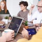 A diverse group of professionals collaborating with laptops and tablets in a modern office setting.